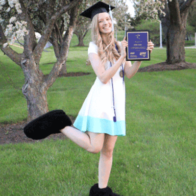 Emmi Carr wearing TK feet and graduation cap with holding an award