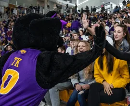 TK high-fiving students in the student section of a basketball game in the McLeod Center.